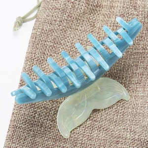 Close-up of a large fishtail hair claw clip in translucent jelly green and grey-blue acetate