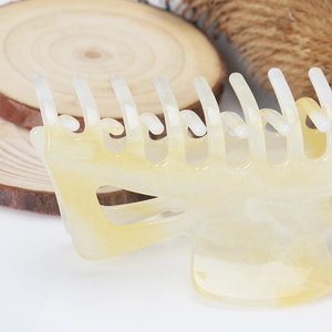 Gros plan sur la pince à cheveux jaune crème pailletée posée sur du bois naturel