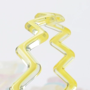 Detailed macro view of the bright yellow wavy resin hair accessory with translucent finish