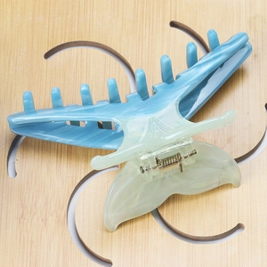 Detail of a large fishtail hair claw with blue and white gradient acetate marble texture