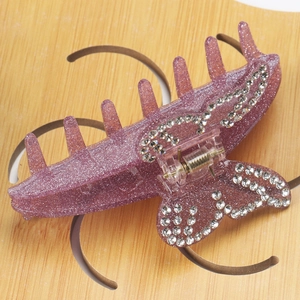 Détail du pince à cheveux papillon pailletée violette avec des décorations en strass brillants