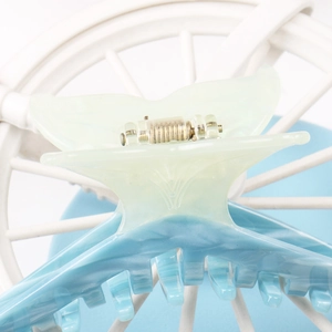 Detail of fishtail-shaped jelly hair claw clip with mint green and blue gradient finish