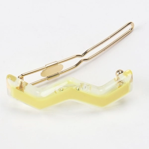 Close-up of yellow wavy resin hairpin with gold metal base in minimalist French style