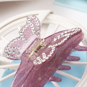 Gros plan sur la pince à cheveux papillon en acrylique violette avec paillettes et strass