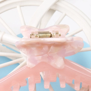 Detail of pink marble butterfly hair claw clip with acetate texture and metal spring