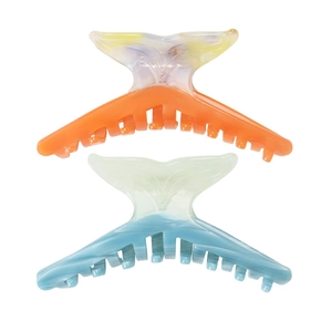 Close-up of fishtail shape hair claws with orange and blue gradient acetate finish