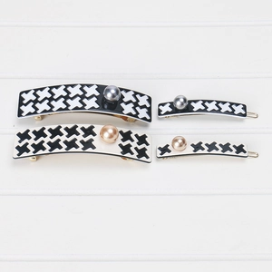 Detailed set of houndstooth hair clips with pearls on a striped background