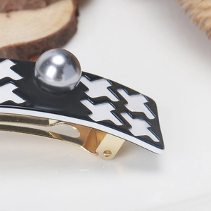 Detail of houndstooth hair clip with silver faux pearl and golden metal base clip