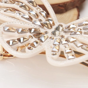 Close-up detail of butterfly hair clip featuring champagne crystals and golden metal clip
