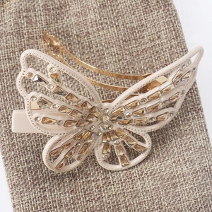 Macro shot of amber crystal butterfly hair clip on textured beige fabric background
