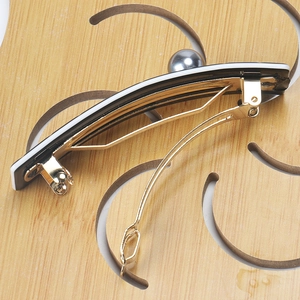 Detailed view of houndstooth hair clip with a grey pearl and golden metal base