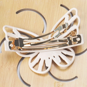 Macro view of cream butterfly hair clip showing golden spring mechanism and FRANCE engraving