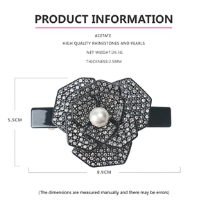 Détail de la pince à cheveux camélia en acétate noir avec strass et perles de mesure
