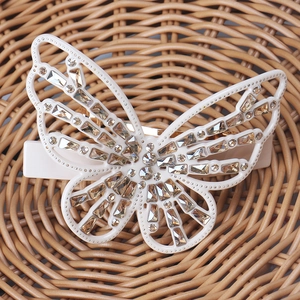 Close-up of cream butterfly hair clip with champagne rhinestones on a woven base