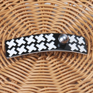 Detail of houndstooth pattern hair clip with a grey pearl and golden metal spring clip