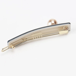 Detailed view of the houndstooth hair clip with gold metal base and faux pearl accent