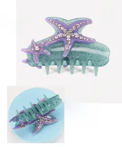 Macro detail of acrylic starfish hair claw with sparkling rhinestones and teal glitter finish