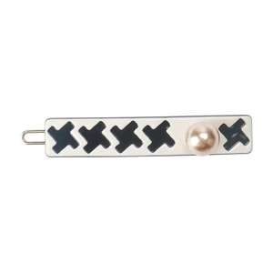 Detailed view of houndstooth hair clip with a gold-tone pearl and resin rectangular base