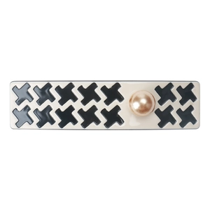 Detail of houndstooth pattern hair clip with black cross design and champagne gold pearl