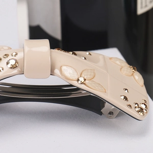 Macro shot of French luxury acetate bow hair clip with champagne rhinestones and floral detail