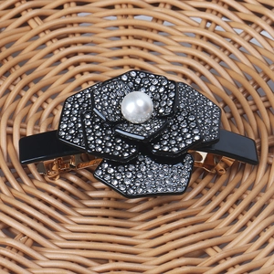 Détail d'une barrette camélia avec strass scintillants et perle blanche au centre