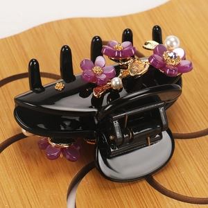 Detailed close-up of a floral hair claw with purple resin flowers and white pearls