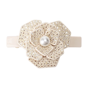 Gros plan détaillé d'une pince à cheveux camélia beige avec strass et une perle centrale
