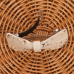 Detailed macro view of a cream bow hair clip featuring champagne diamonds and flowers