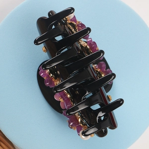 Detailed macro view of acetate floral hair claw with purple petals and white pearls