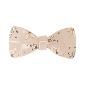 Close-up of elegant beige acetate bow hair clip with sparkling rhinestones and floral details