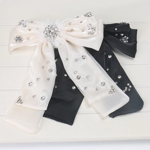 Détail de grandes barrettes nœuds en satin avec strass brillants en noir et blanc