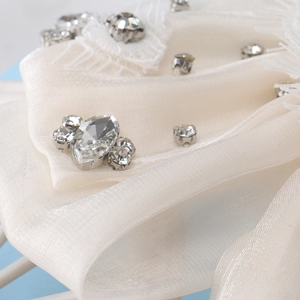 Macro d'un nœud en organza blanc cassé avec bordure en dentelle et strass scintillants