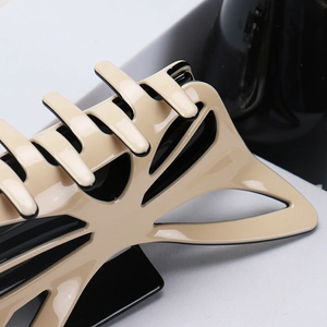 Close-up of a large cream and black bow hair claw clip with a high-gloss polished finish