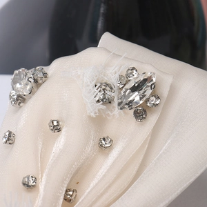 Détail d'un nœud en satin blanc crème avec cristaux brillants et maille d'organza fine