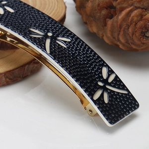 Macro shot of dark blue dragonfly hair clip with golden metal clip on natural wood