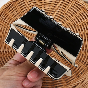 Detail of large black and cream acetate hair claw clip with gold metal spring hinge