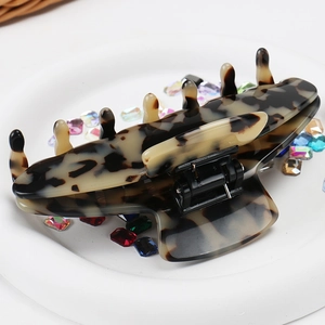 Detailed view of a large leopard print hair claw clip on a white decorative tray