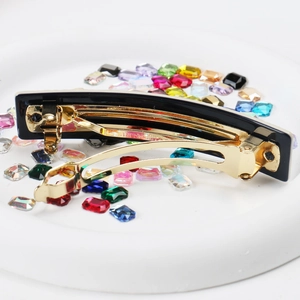 Detail shot of black acetate spring hair clip with Made in France gold metal engraving