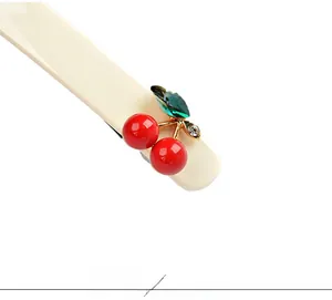 Détail macro d'une barrette cerise en acétate avec fruits rouges et feuilles en strass