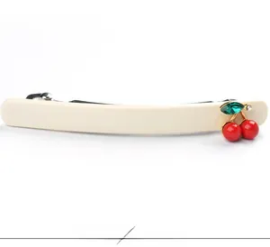 Détail d'une barrette en acétate crème avec motif cerises rouges et feuille en cristal vert
