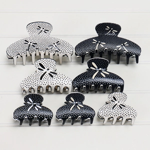 Detail view of premium acetate hair claw set in black and white with dragonfly pattern
