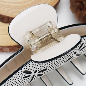 Detail of elegant beige acetate hair claw featuring hollow butterfly patterns and metal spring