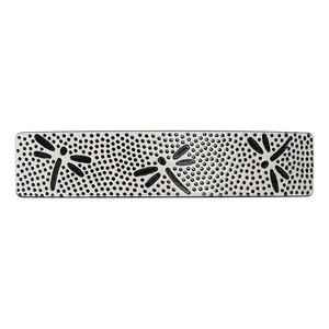 Detail of vintage cream acetate hair clip featuring black polka dots and dragonfly patterns