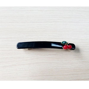Détail de la barrette en acétate noir avec cerises rouges et feuille en pierre précieuse