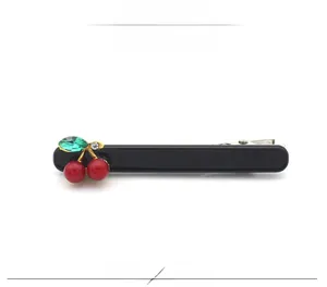 Détail de la barrette cerise en acétate avec perles rouges et gemme verte sur base noire