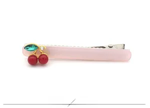 Détail de la barrette en acétate rose avec perles cerises rouges et feuille en cristal