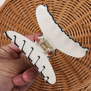 Detailed view of a large acetate hair claw clip with cream base and black wavy edge