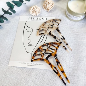 Close-up of fan-shaped acetate hair forks with tortoise patterns and sparkling rhinestones