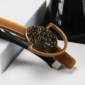 Macro shot of amber resin hair clip featuring glittering rhinestones and gold accents