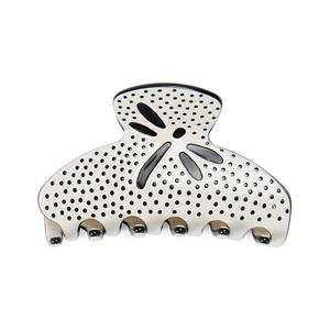 Detail view of cream hair claw clip with black polka dots and hollow dragonfly pattern